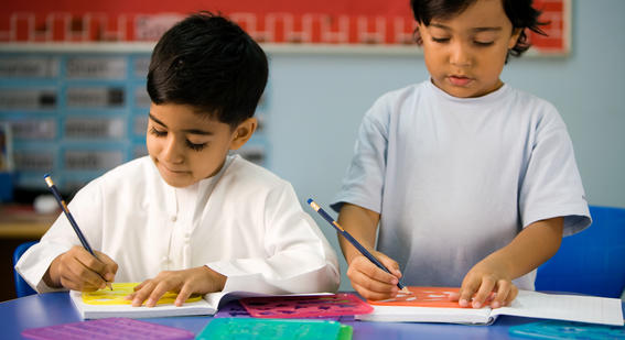 Two children use stencils in a classroom.
