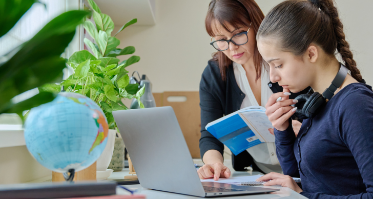Teacher helping a learner at a laptop.