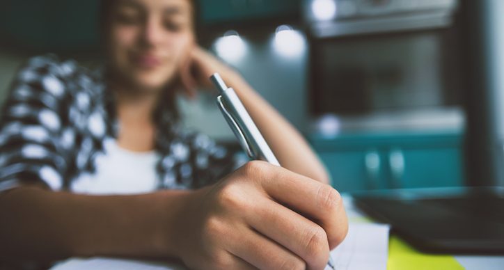 Getting creative with stories - A teenager sits writing in her notebook